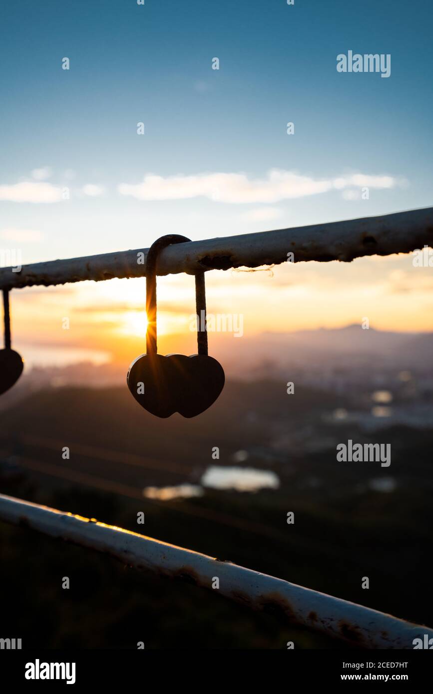 Close-up of heart-shaped silhouette of love lock hanging on fence in back lit of sunset in Phoenix Park, Sanya, China Stock Photo