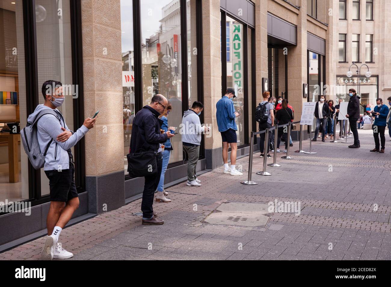 to comply with the distance rules during the Corona pandemic, customers are waiting in front of the Apple Store on Schildergasse, Cologne, Germany.  z Stock Photo