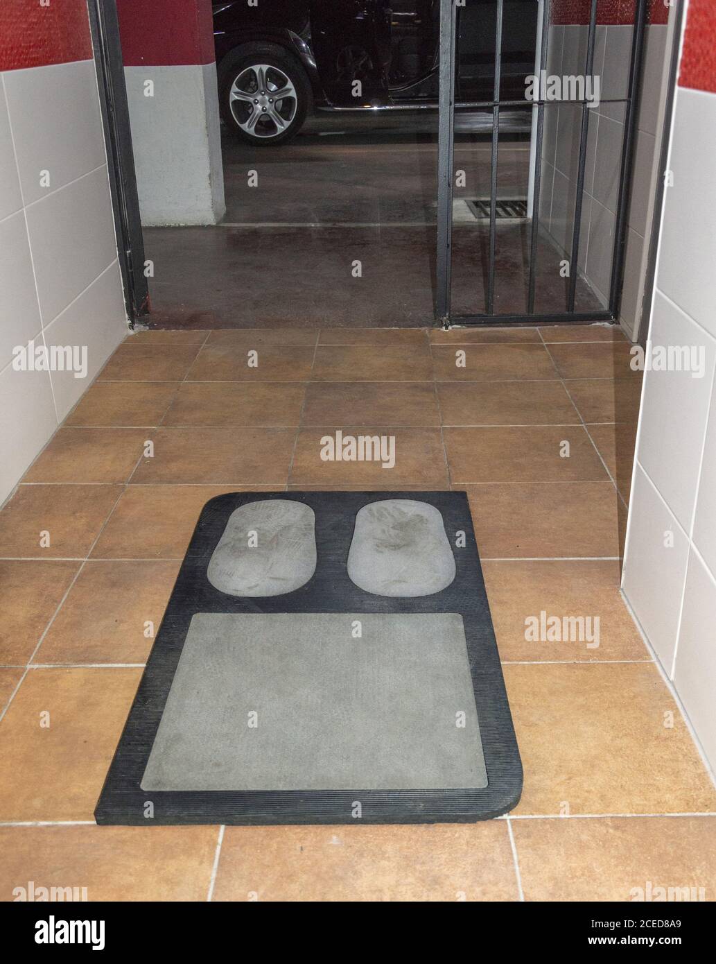 Cleaning shoe soles on a carpet with disinfectant liquid before leaving