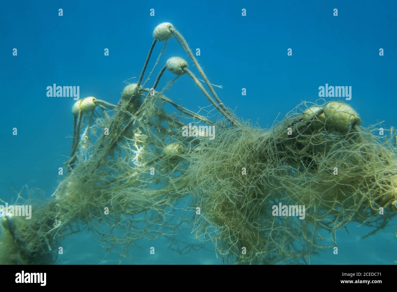 Lost fishing net with buoys lies underwater on the seabed on blue water background. Becici, Budva Municipality, Montenegro Stock Photo