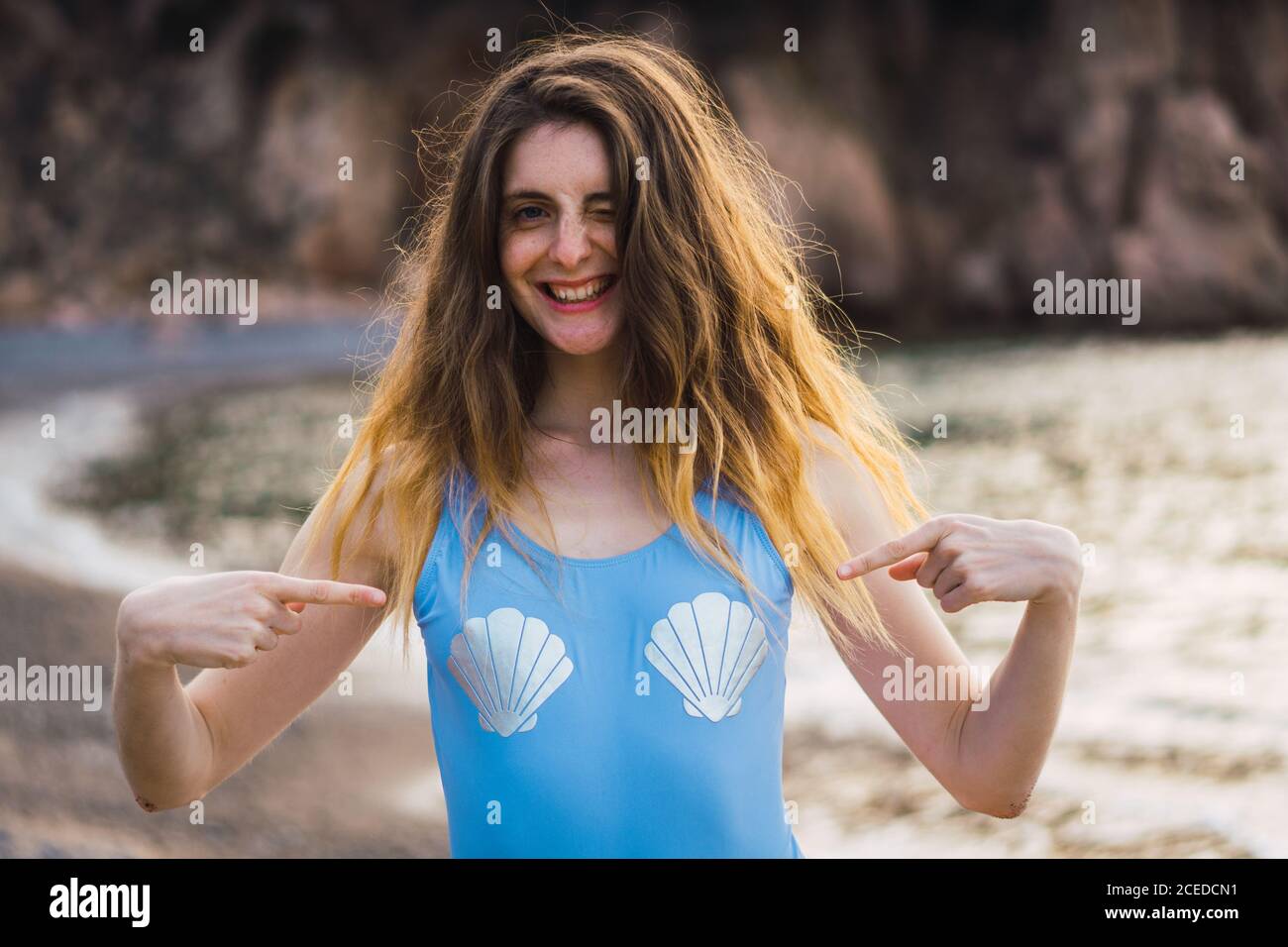 Winking and smiling Woman pointing on shells print on swimsuit on the ...