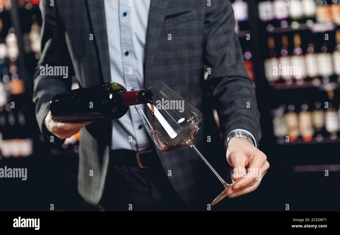 Sommelier pouring red wine into long-stemmed glasses Stock Photo