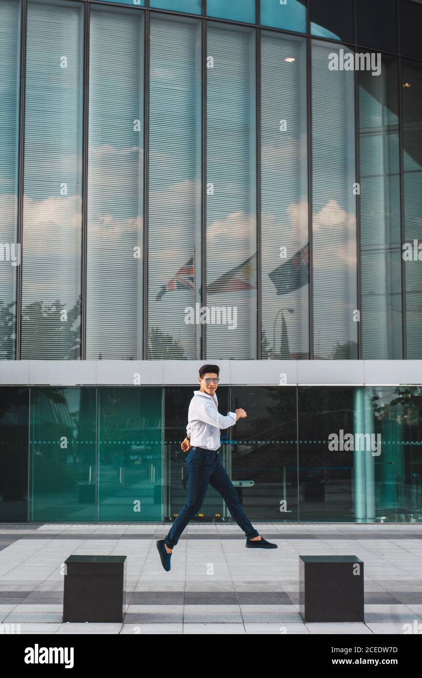 man jumping on pavement of highrise Stock Photo