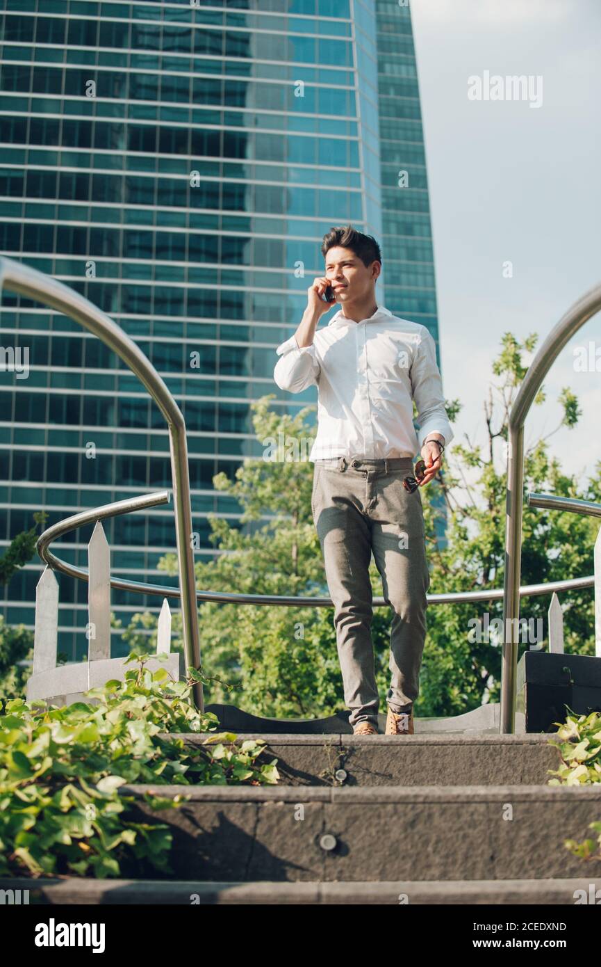 Cheerful man with smartphone walking down steps Stock Photo