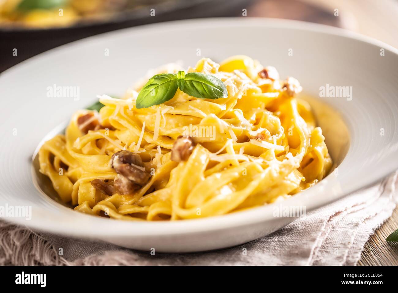 Italian food pasta tagliatelle carbonara with pancetta parmesan egg yolk and basil leaves Stock Photo