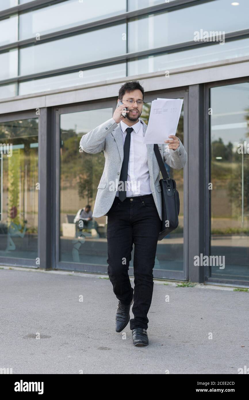 Latin businessman, leaving work from his office with his laptop and talking on the phone Stock Photo