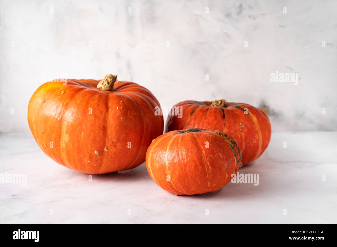 Three orange pumpkins with different size on white background Stock Photo