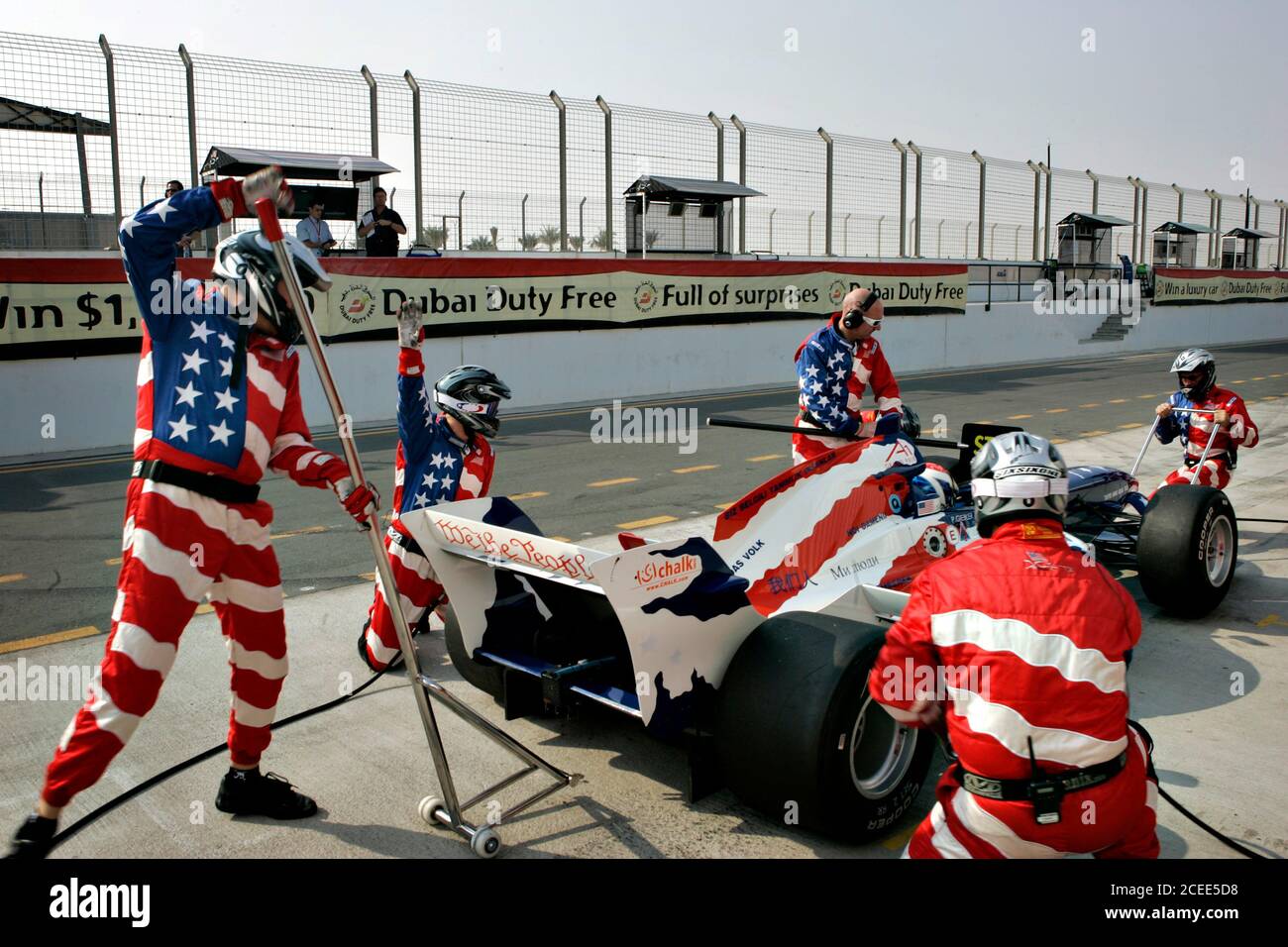 Men preparing race car for race wearing stars and stripes suits in