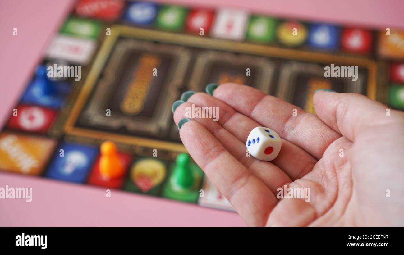 Hand throws the dice on the background of colorful blurred Board games