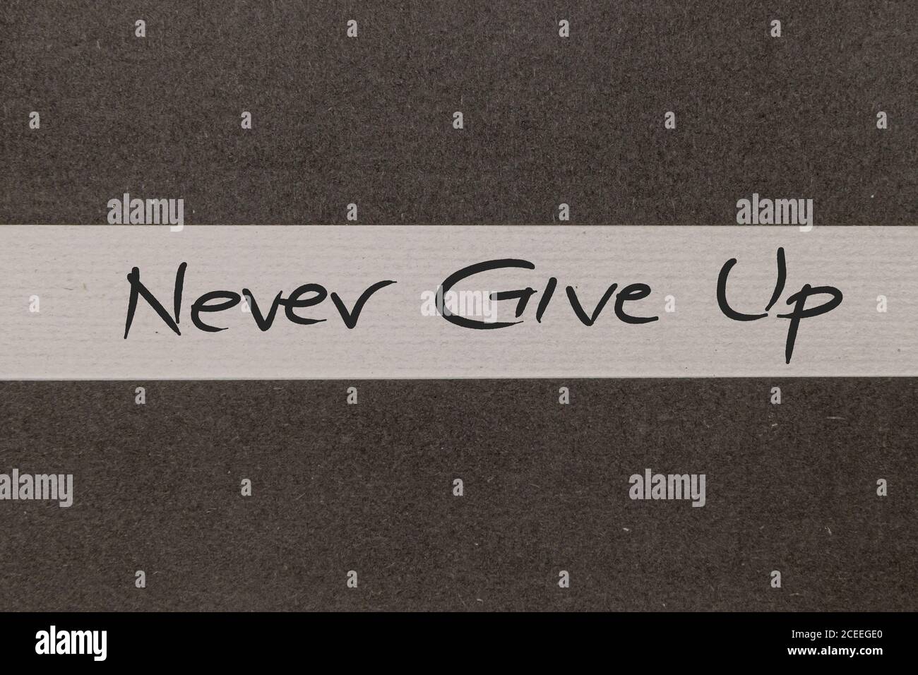 White and Grey coloured paper background with Never Give Up motivational handwritten message Stock Photo