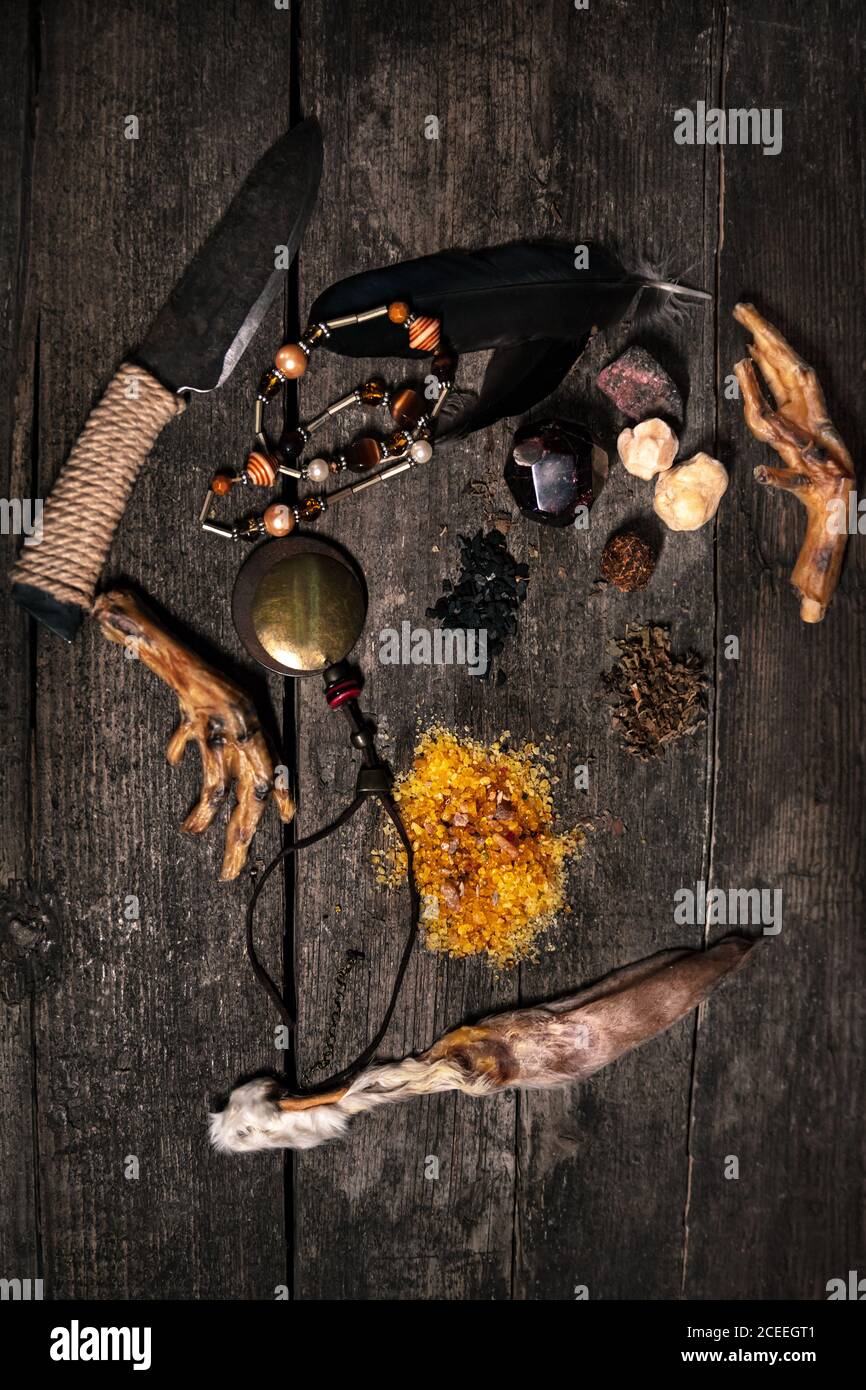 Black or dark ingredients for an ritual, voodoo or occultims materials on wooden table, rabbit ear, crow´s feet, knife, talisman and incense Stock Photo