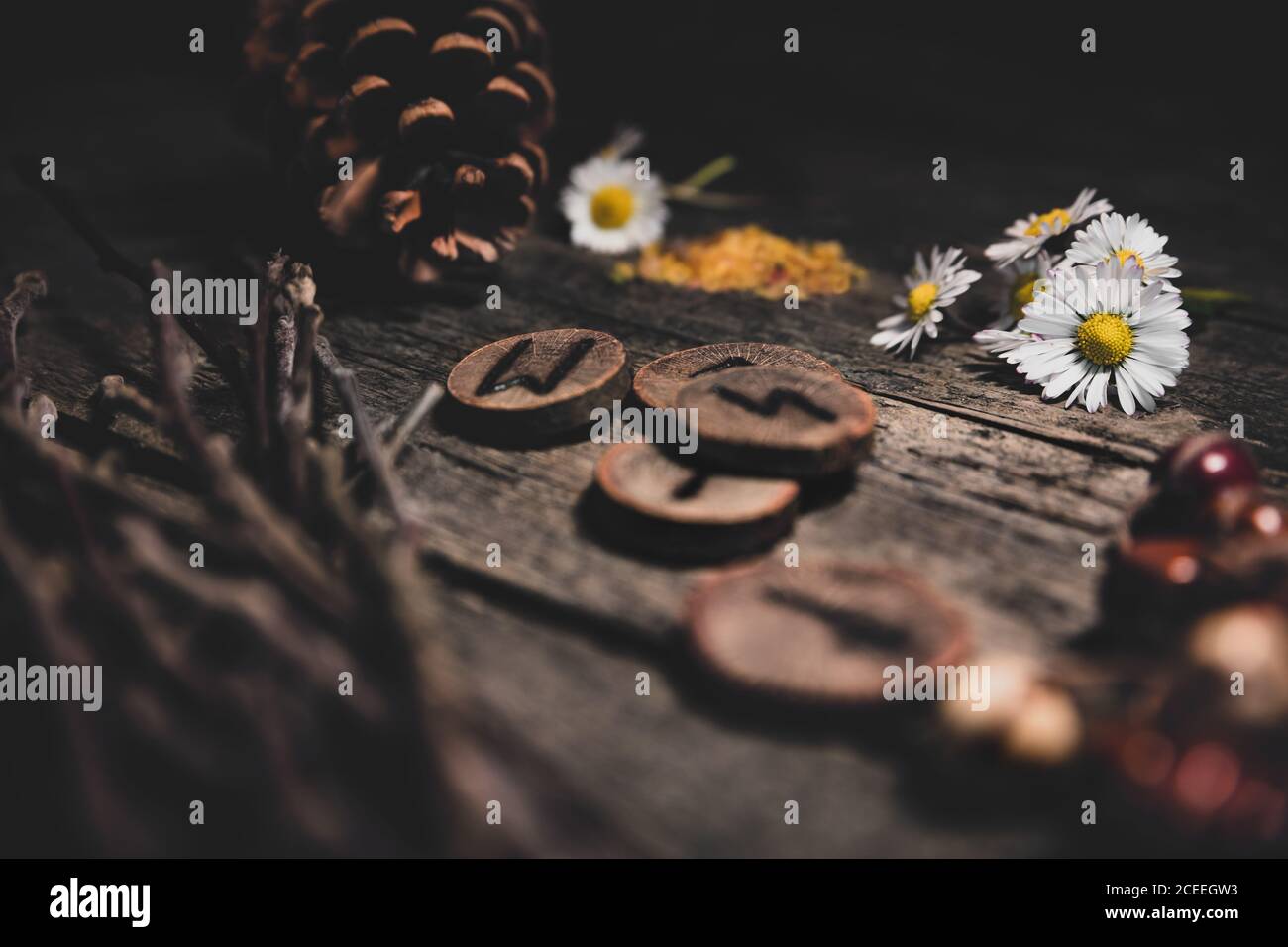 Natural esoteric background with elder runes or futhark, flowers and cones, wooden table Stock Photo