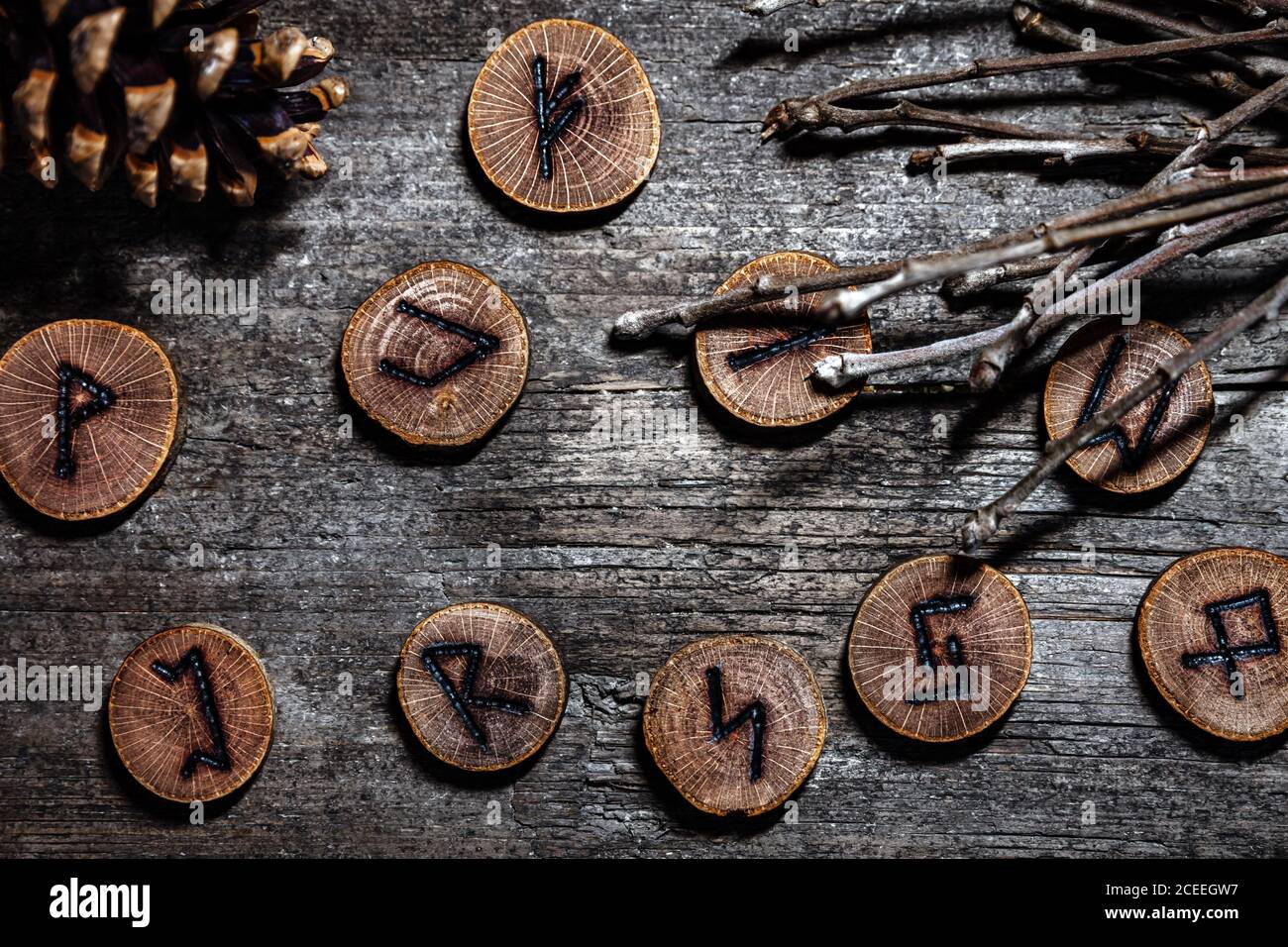 Elder runes or furthark with twigs and a cone, naturally esoteric background on wooden table Stock Photo