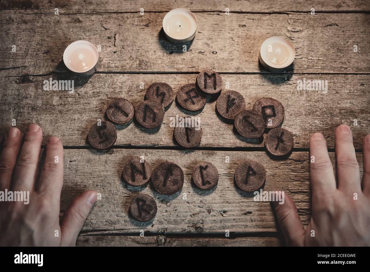 Flatlay, elder runes or futharks with candles and hands on wooden table, esoteric and spirituality, brown background Stock Photo