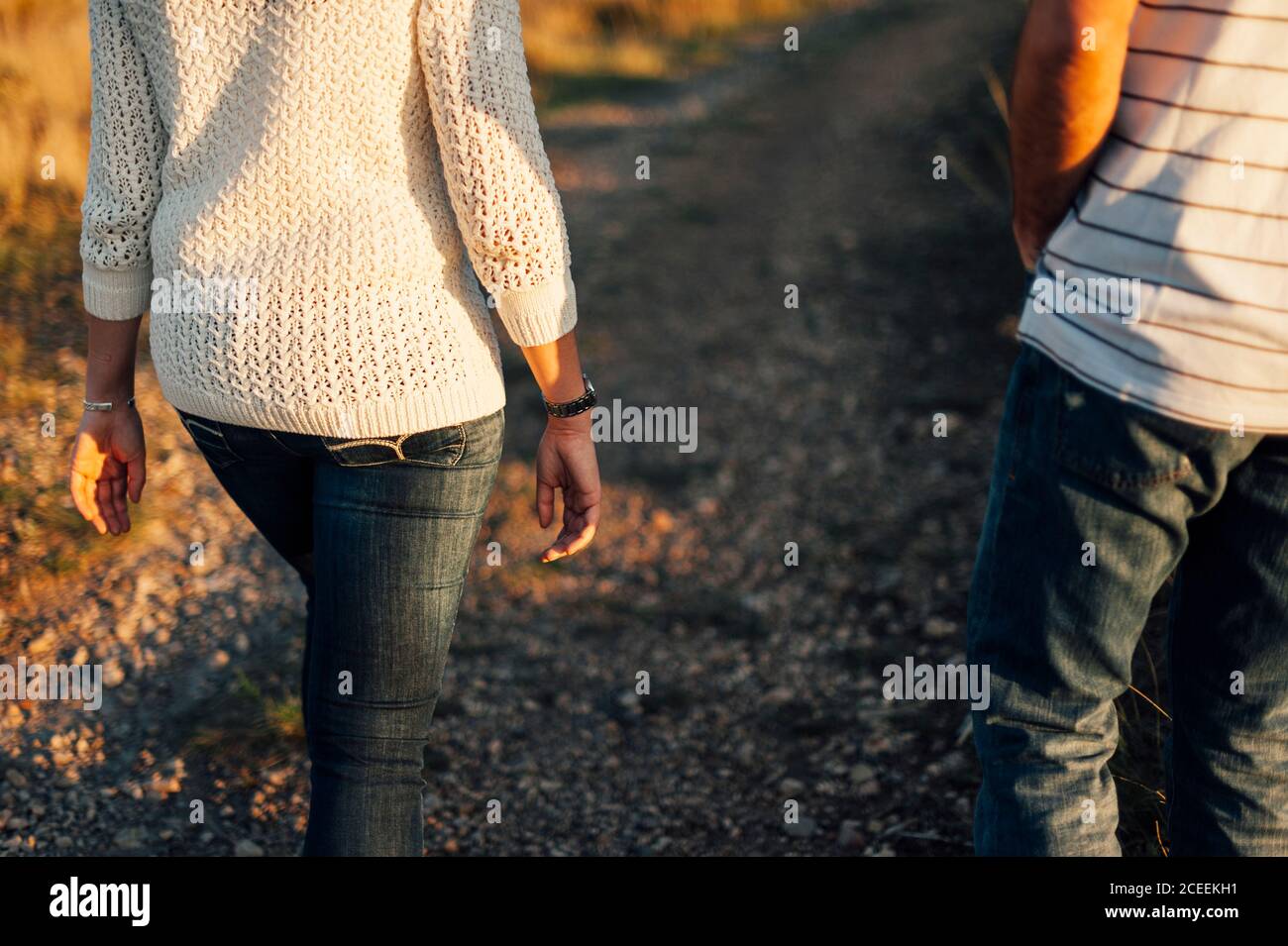 Back view of crop couple walking on rural road in sunlight Stock Photo ...