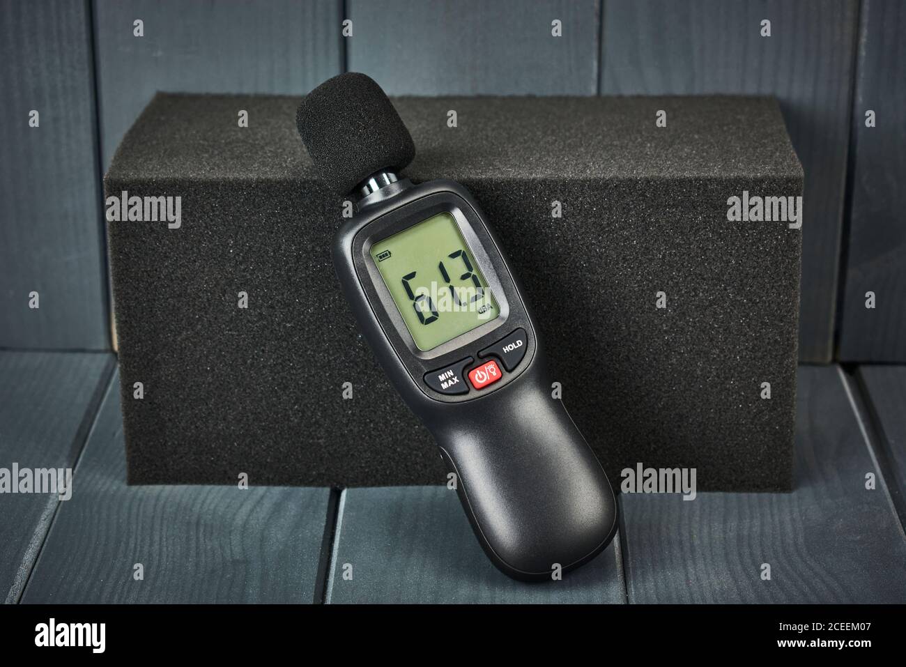 Digital sound level meter on acoustic foam in gray wooden space Stock Photo