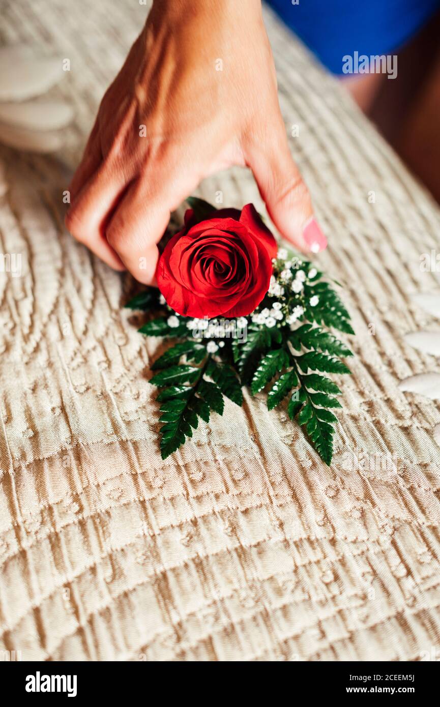 Hand of unrecognizable person taking red rose decoration from the table. Stock Photo