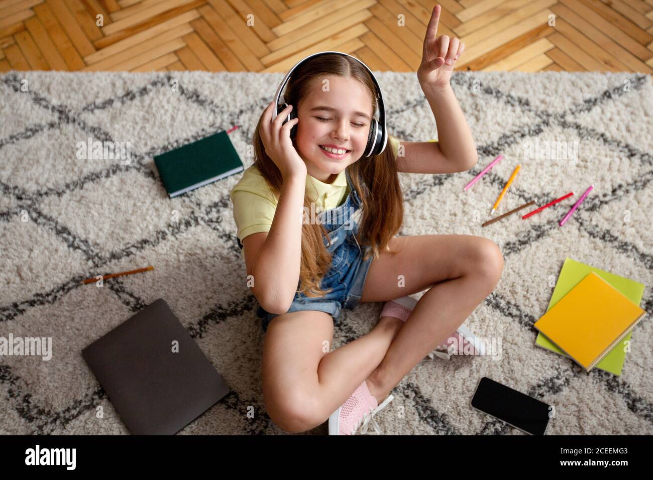 Girl listening to music sitting on the carpet Stock Photo - Alamy