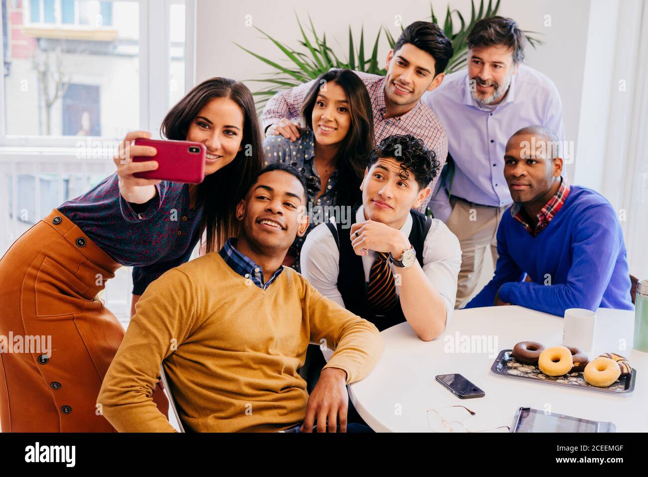 Multiracial team standing and sitting while taking selfie at the table in office. Stock Photo