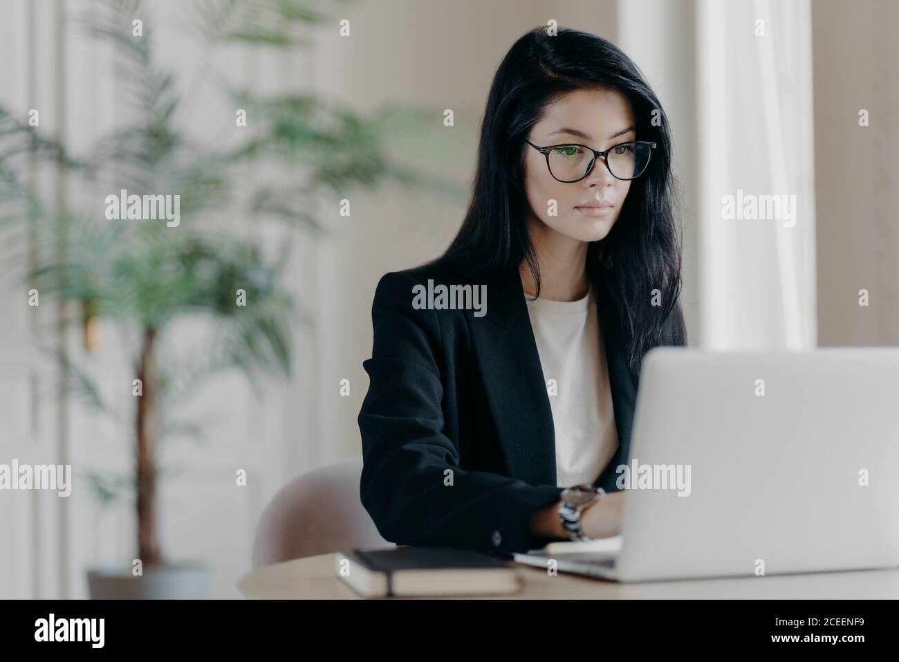 Young serious businesswoman works with laptop computer at workplace in