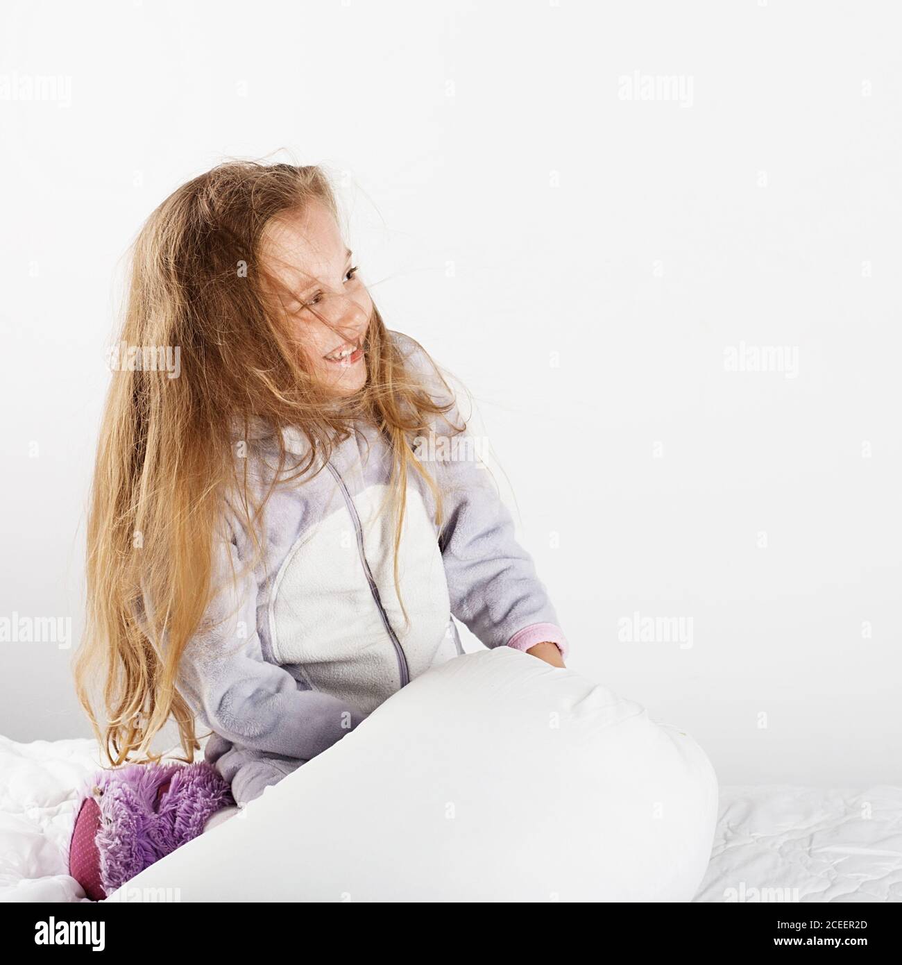 Cute little girl in pajamas jumping and having fun in bed at home ...
