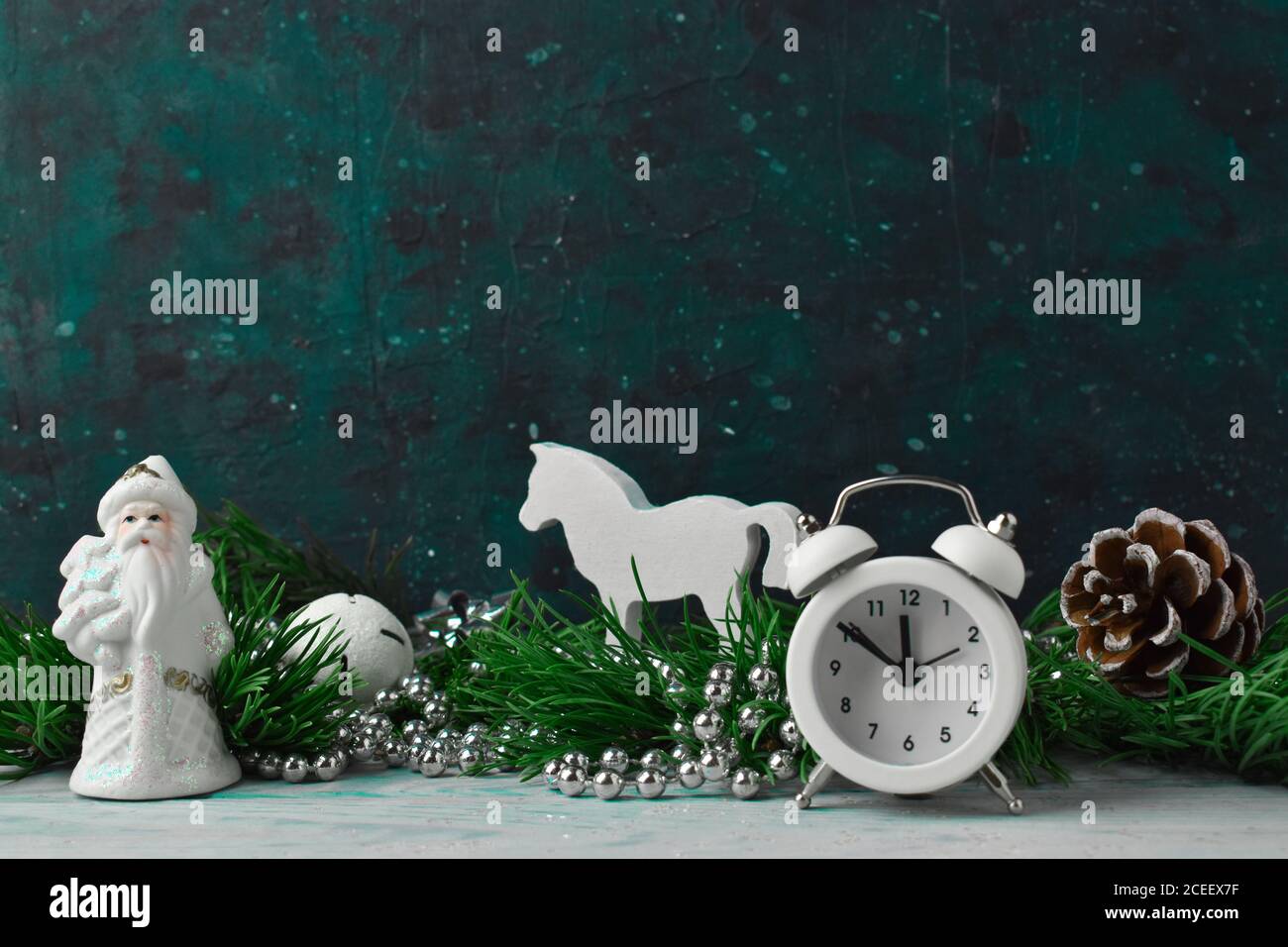 Christmas composition with pine branches and white Christmas decorations and a clock on a cosmic background Stock Photo