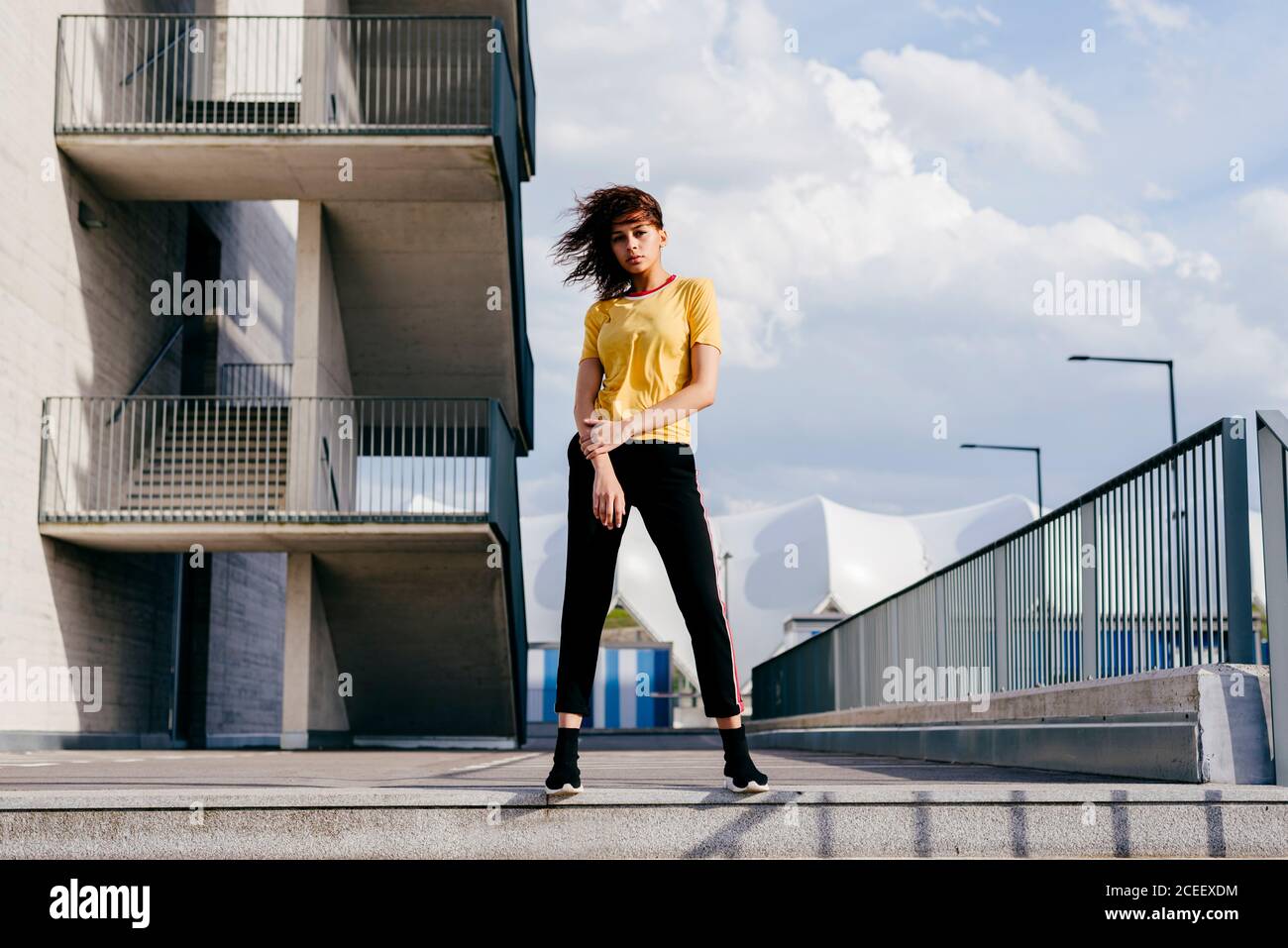 Pretty young Woman in sportswear standing on the street and looking at camera. Stock Photo