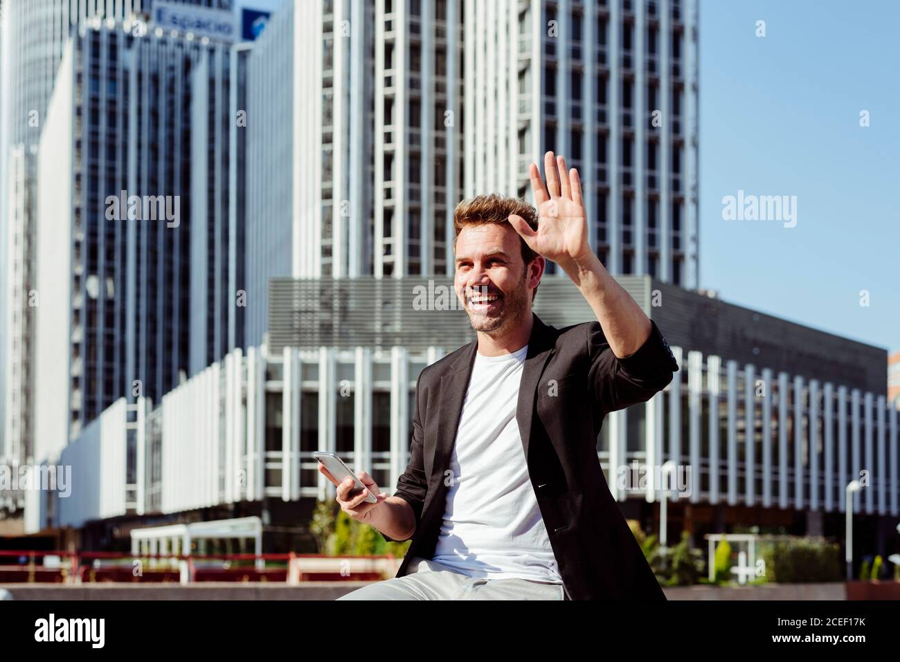 man browsing smartphone on bench and greeting Stock Photo