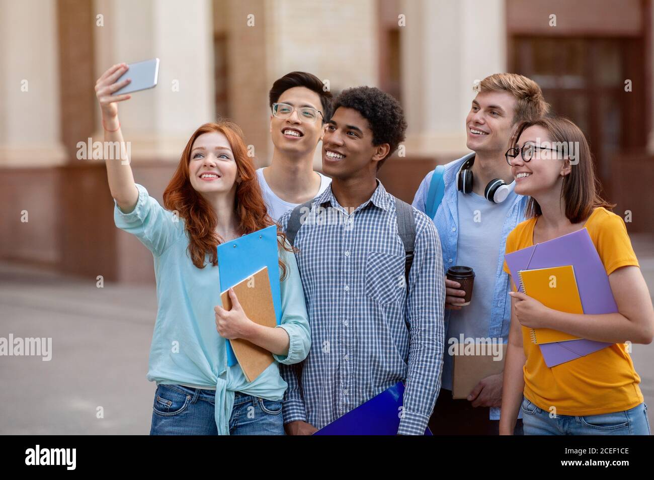 Happy Student Girl Making Group Selfie With Coursemates Standing Outdoor Stock Photo