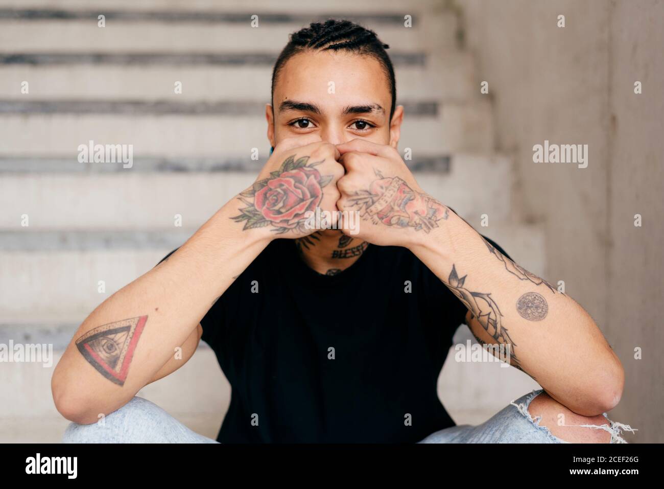 Hispanic man wearing casual clothes sitting on stairs and looking at camera Stock Photo
