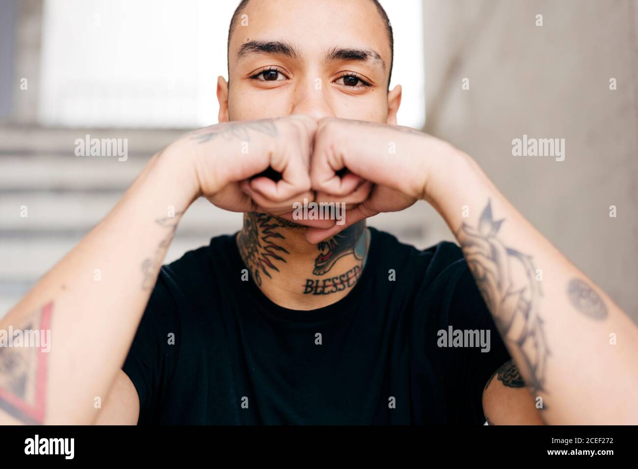 Hipster covering face with tattooed hands Stock Photo