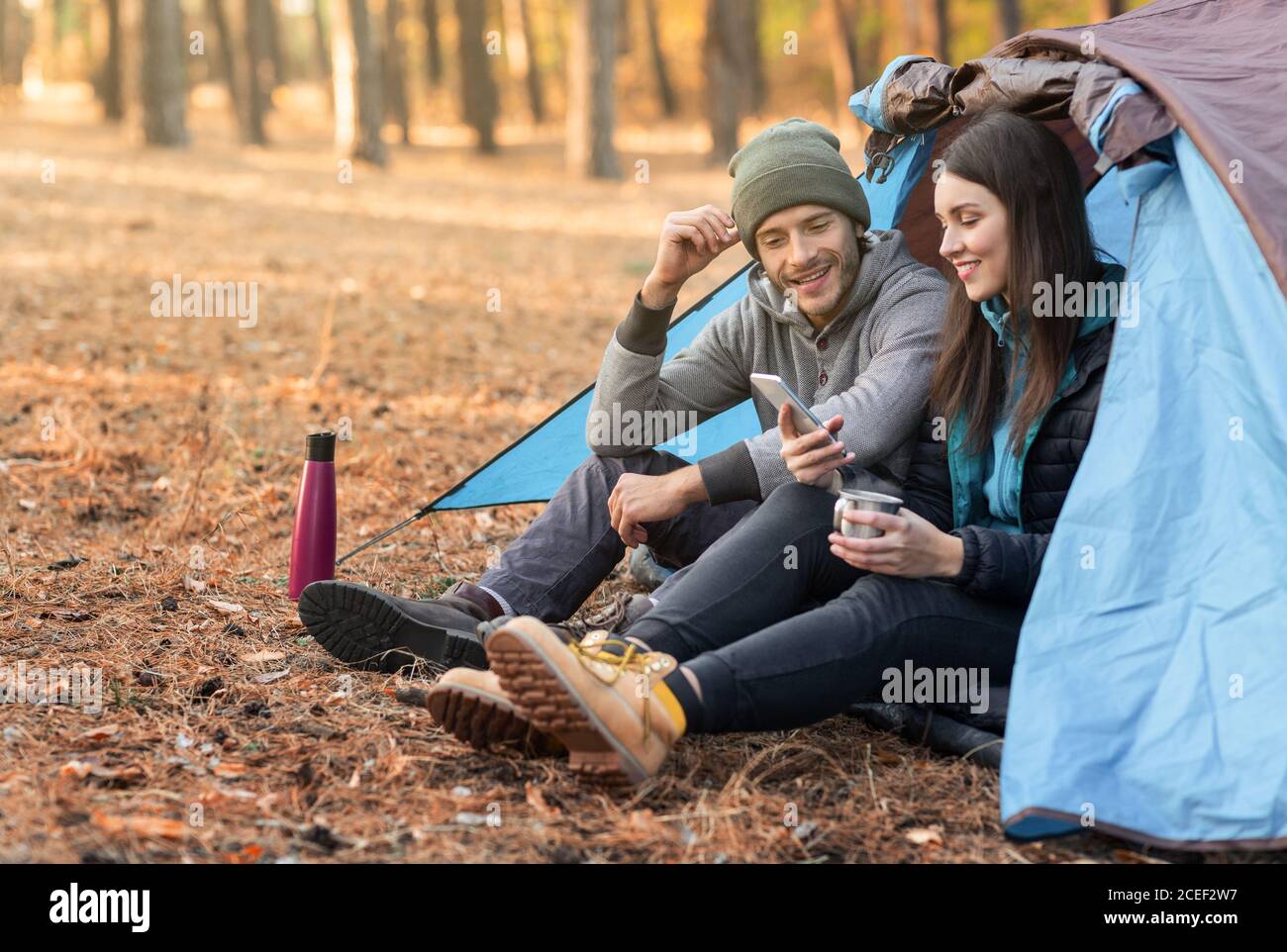 Romantic couple camping outdoors, sitting in tent and talking Stock ...