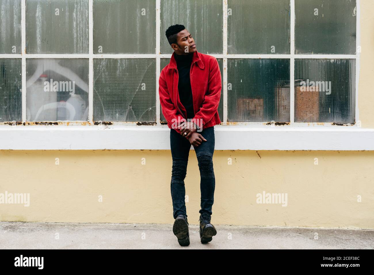 Serious young black male wearing red jumper outdoors Stock Photo
