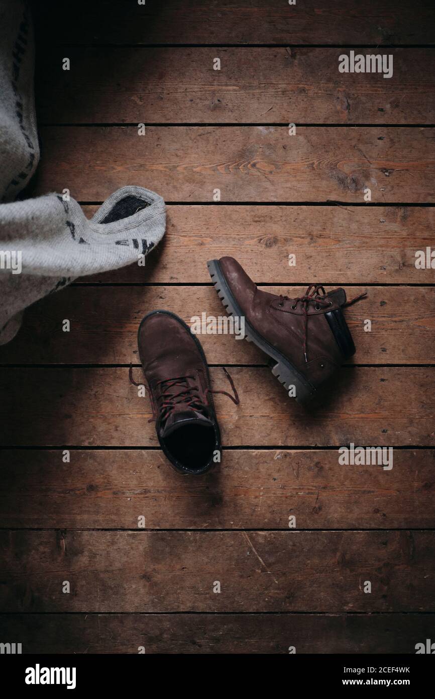 From above brown leather unleashed boots taken off on wooden floor Stock Photo
