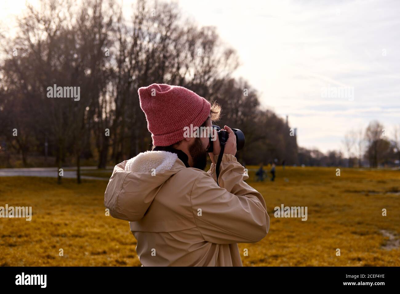 Side view of photographer man standing and taking shots in the park in Munich Stock Photo