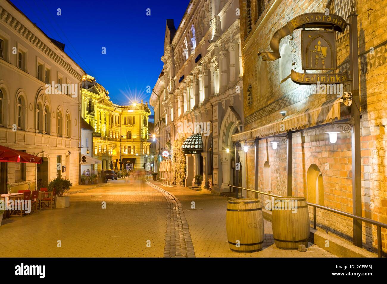 Night view of illuminated Ausros Vartu Street in the Old Town of Vilnius, Lithuania. Medininkai Restaurant and Royale Hotel on the right. Lithuanian N Stock Photo