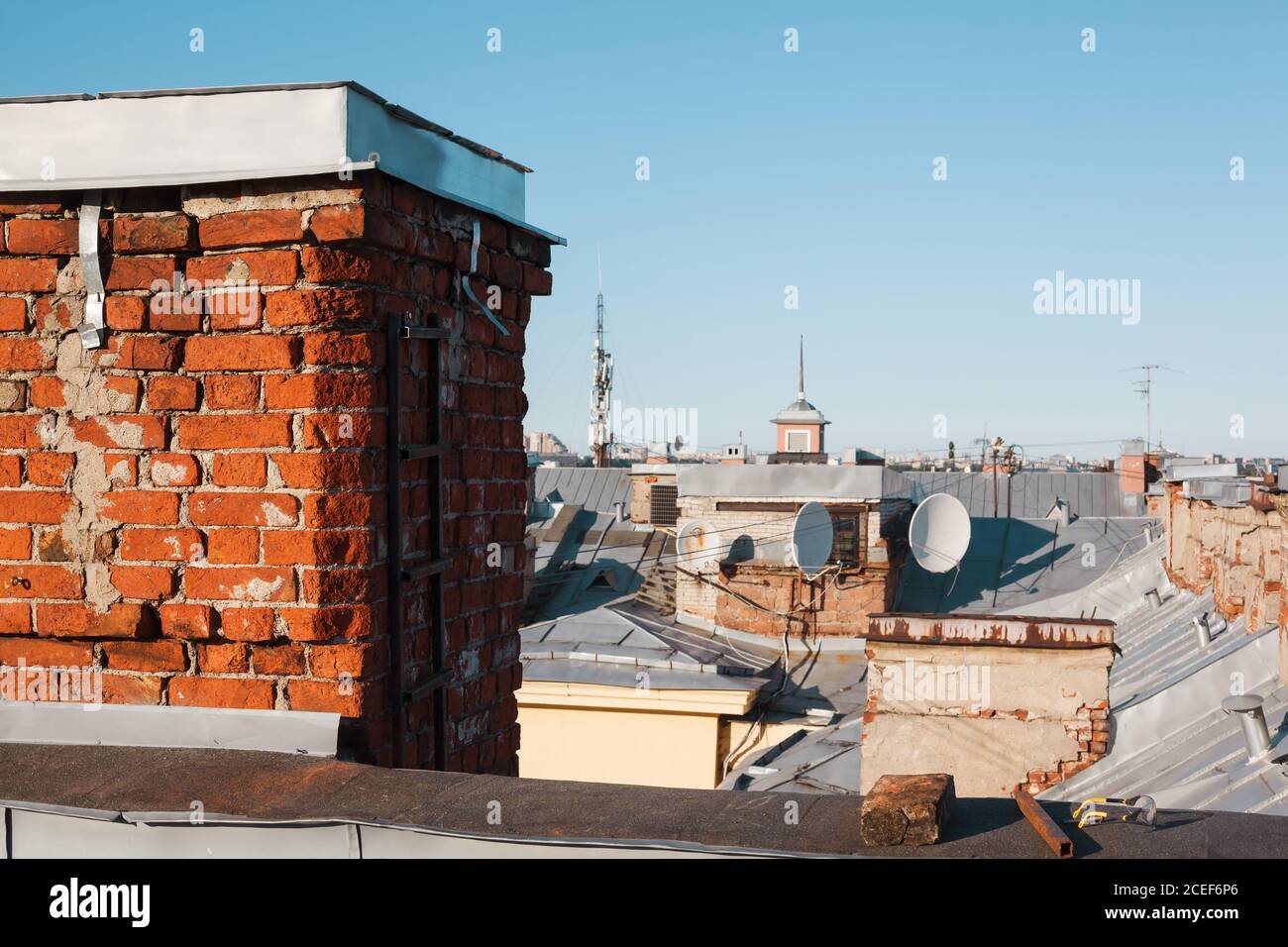 Old brick chimney pipe on a roof of residential building with copy space, satellite dish or 4g antenna installation Stock Photo