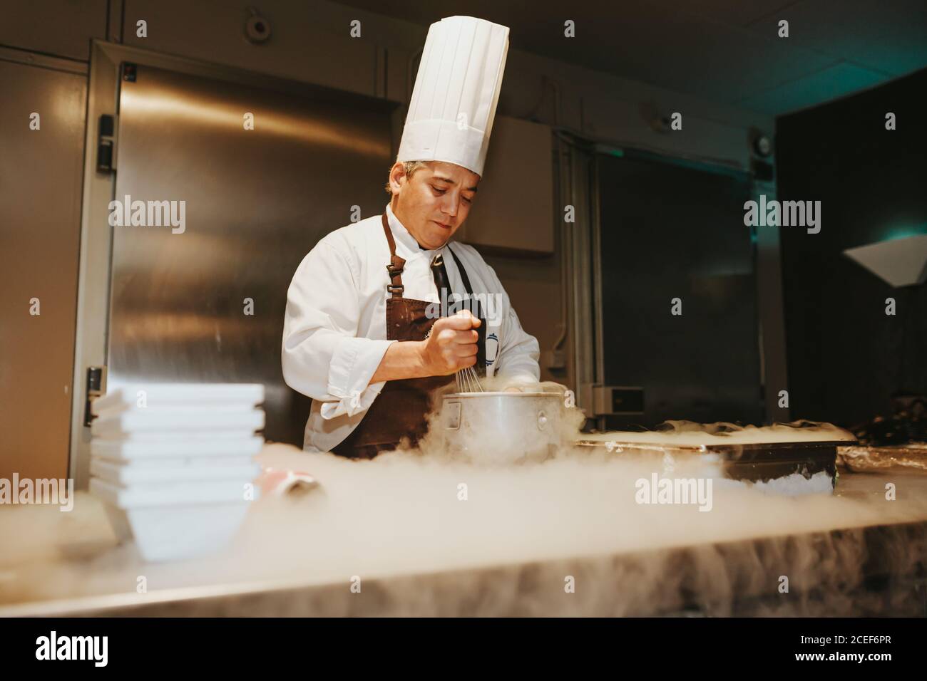 A person making a cold dish with the steam on a table. Horizontal indoors shot. Stock Photo