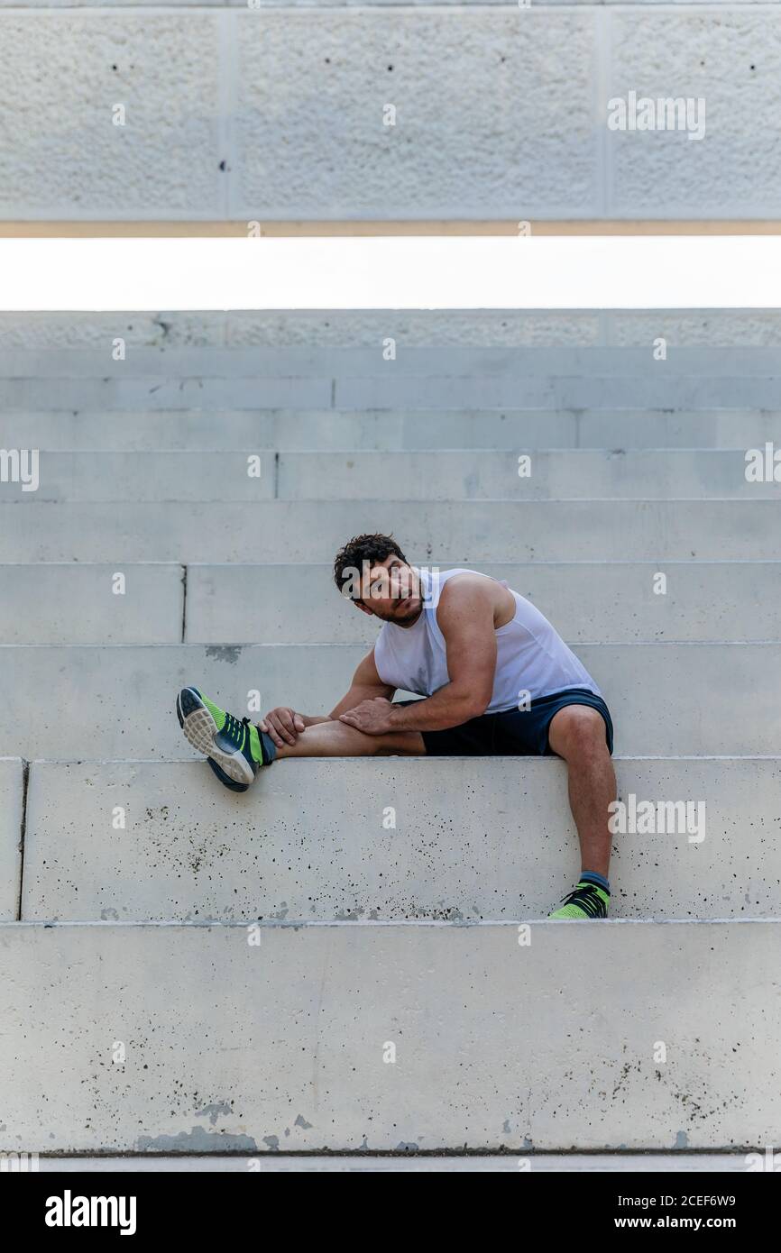 Tired sportsman stretching on steps Stock Photo