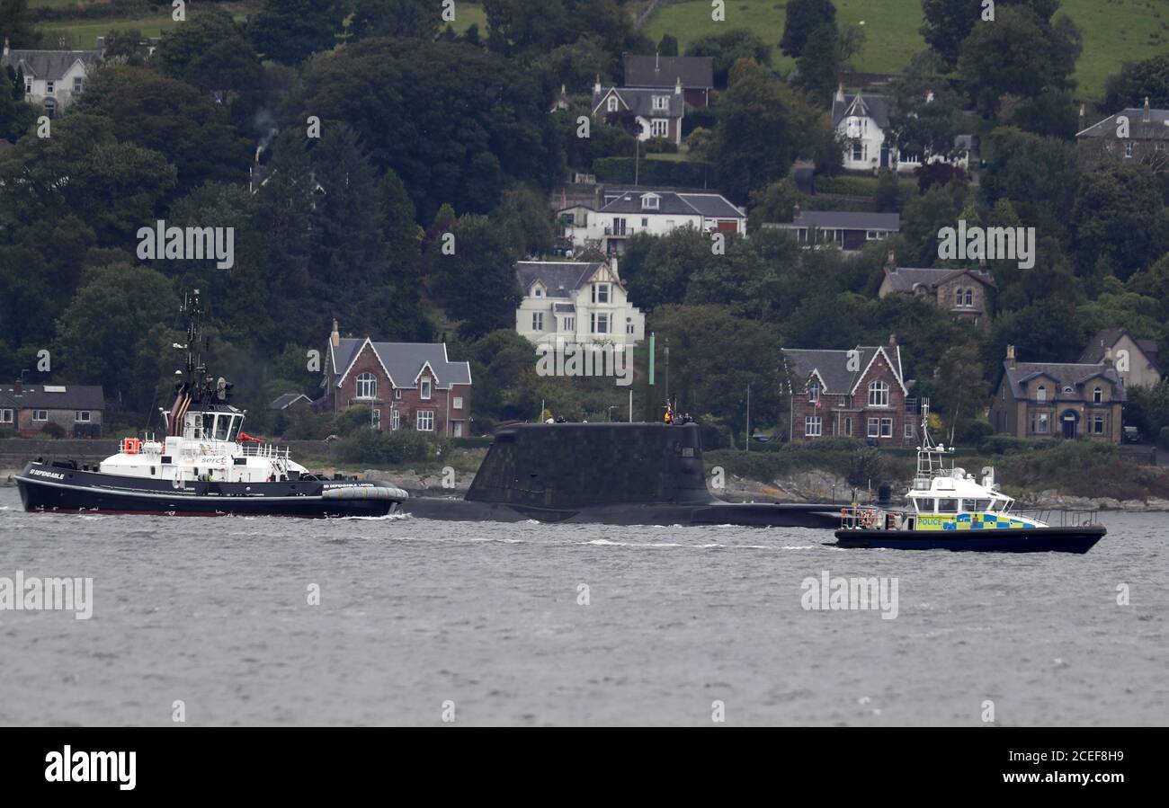 A police patrol boat goes to move on a sailing boat as one of the Royal Navy's seven Astute-class nuclear-powered attack submarine passes through the water at the entrance to Holy Loch and Loch Long near Kilcreggan, in Argyll and Bute. Stock Photo