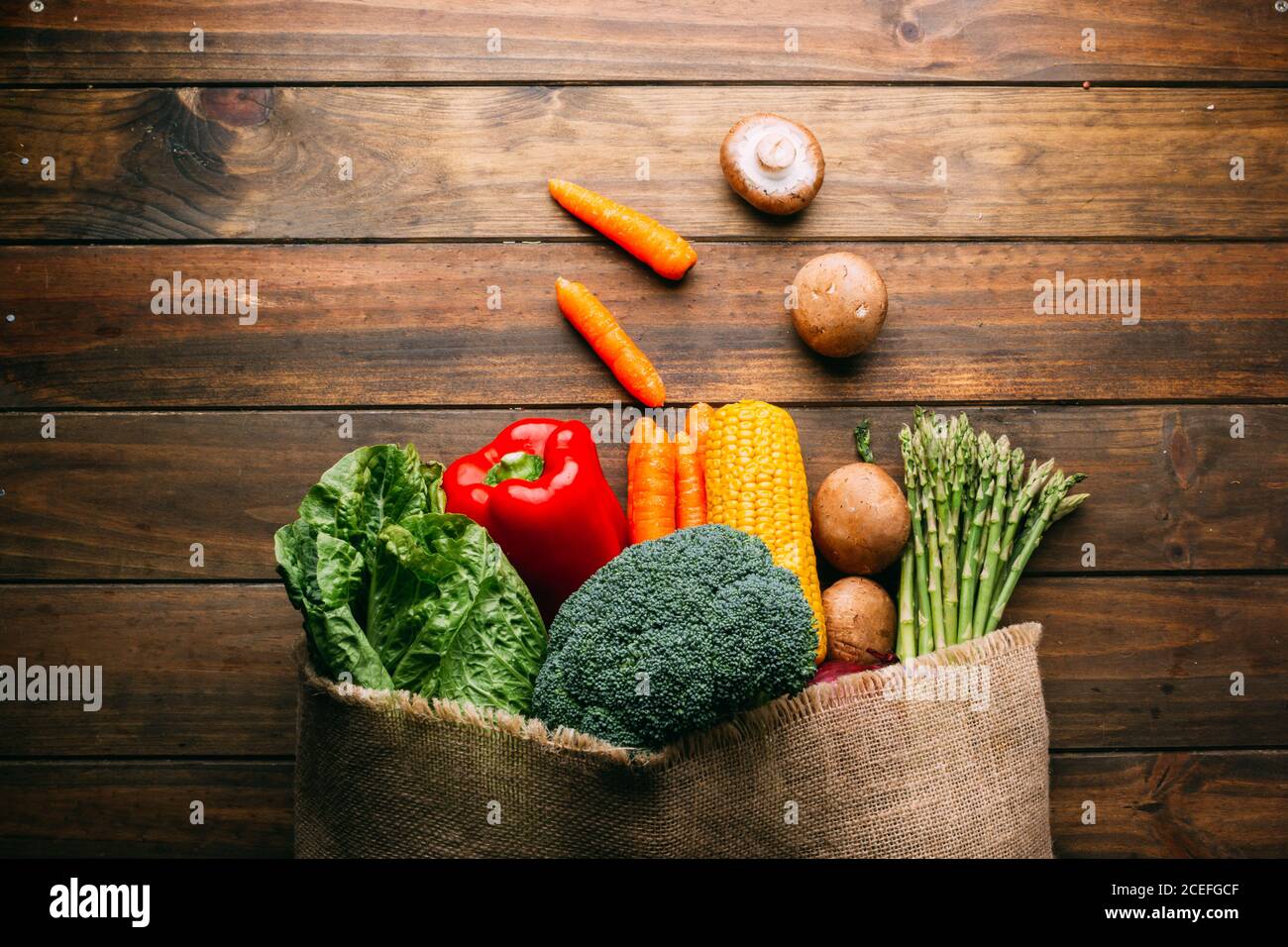 Linen sack with assorted vegetables on table Stock Photo