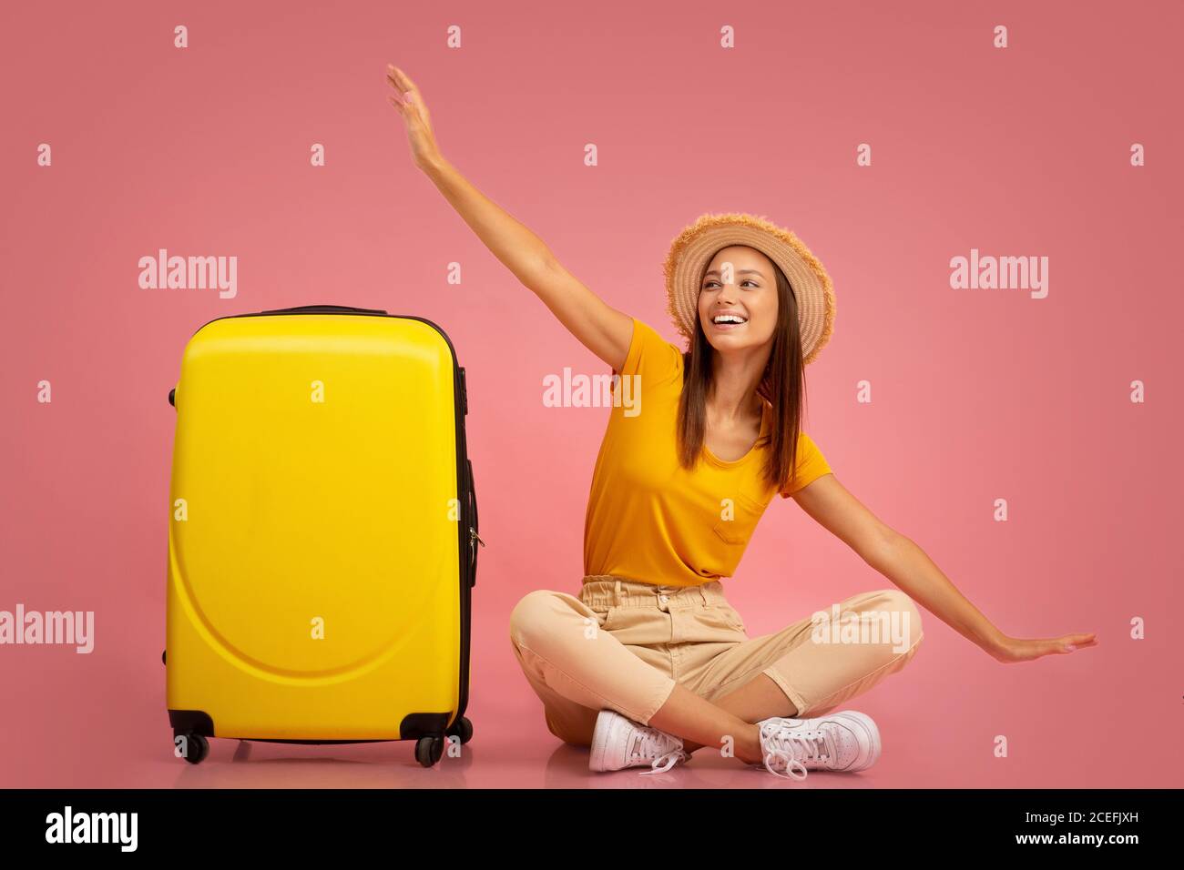 Girl sitting next to suitcase, imitating airplane Stock Photo