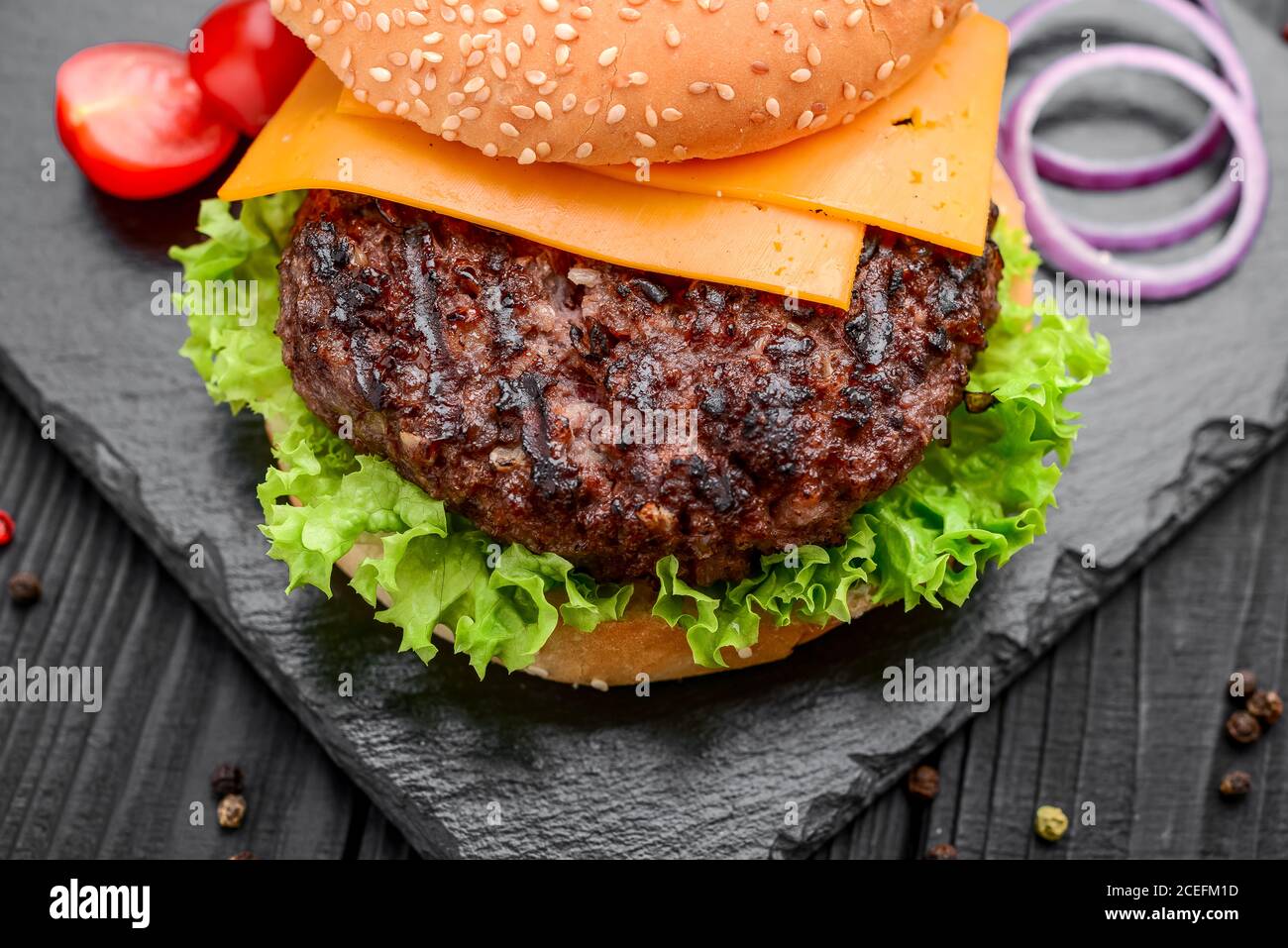 Homemade burger with salad and cheese. Laid out on black slate Stock Photo