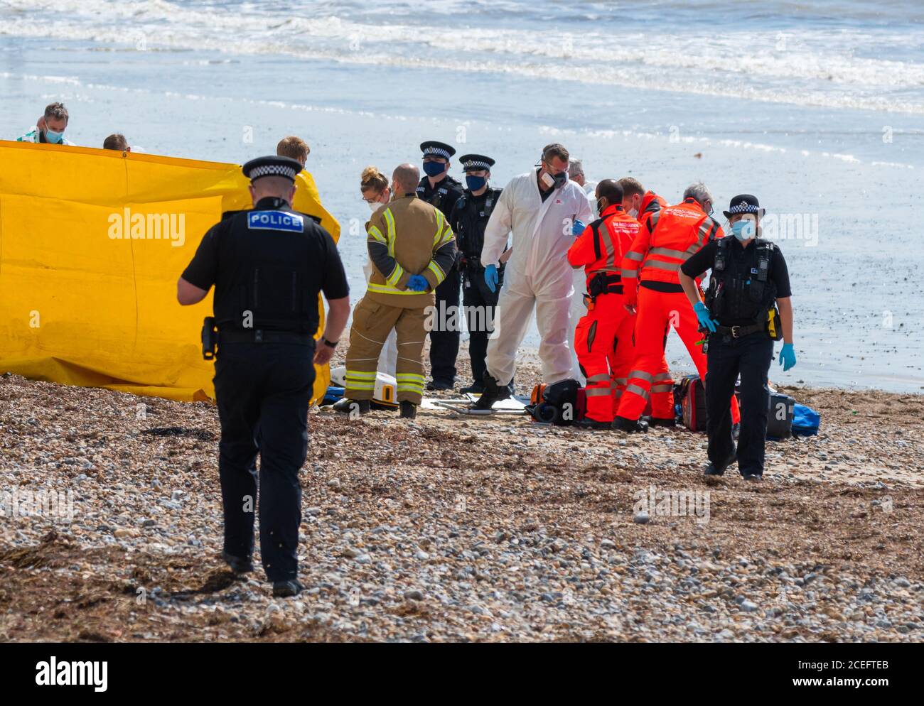 Emergency Services (police, fire, air ambulance, paramedics) at an incident on a beach in the UK. All wearing face masks due to COVID19 Coronavirus. Stock Photo