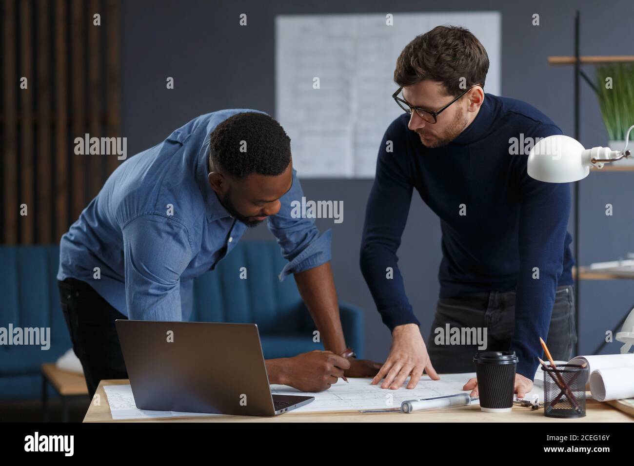 Multiracial engineer team working in office with blue prints and ...