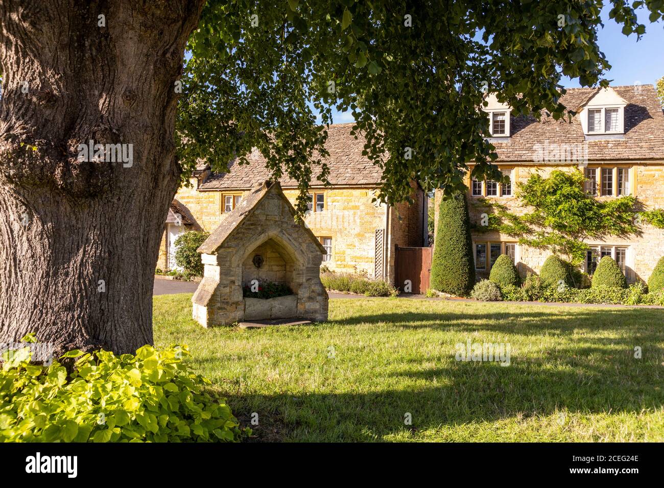 Evening light on cottages beside the village green in the Cotswold village of Lower Slaughter, Gloucestershire UK Stock Photo