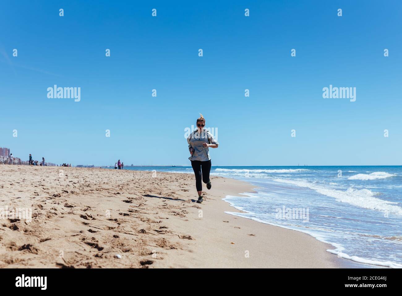 Woman running along the shore of the beach Stock Photo - Alamy