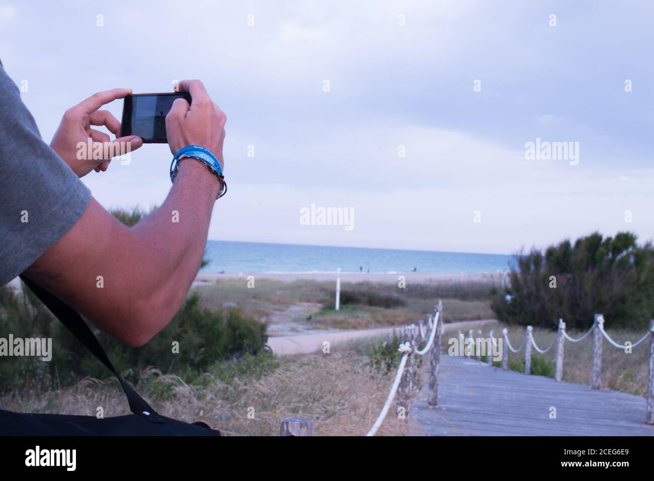 vista de los brazos de un chico fotografiando con su móvil el precioso paisaje de la playa del saler en valencia Stock Photo