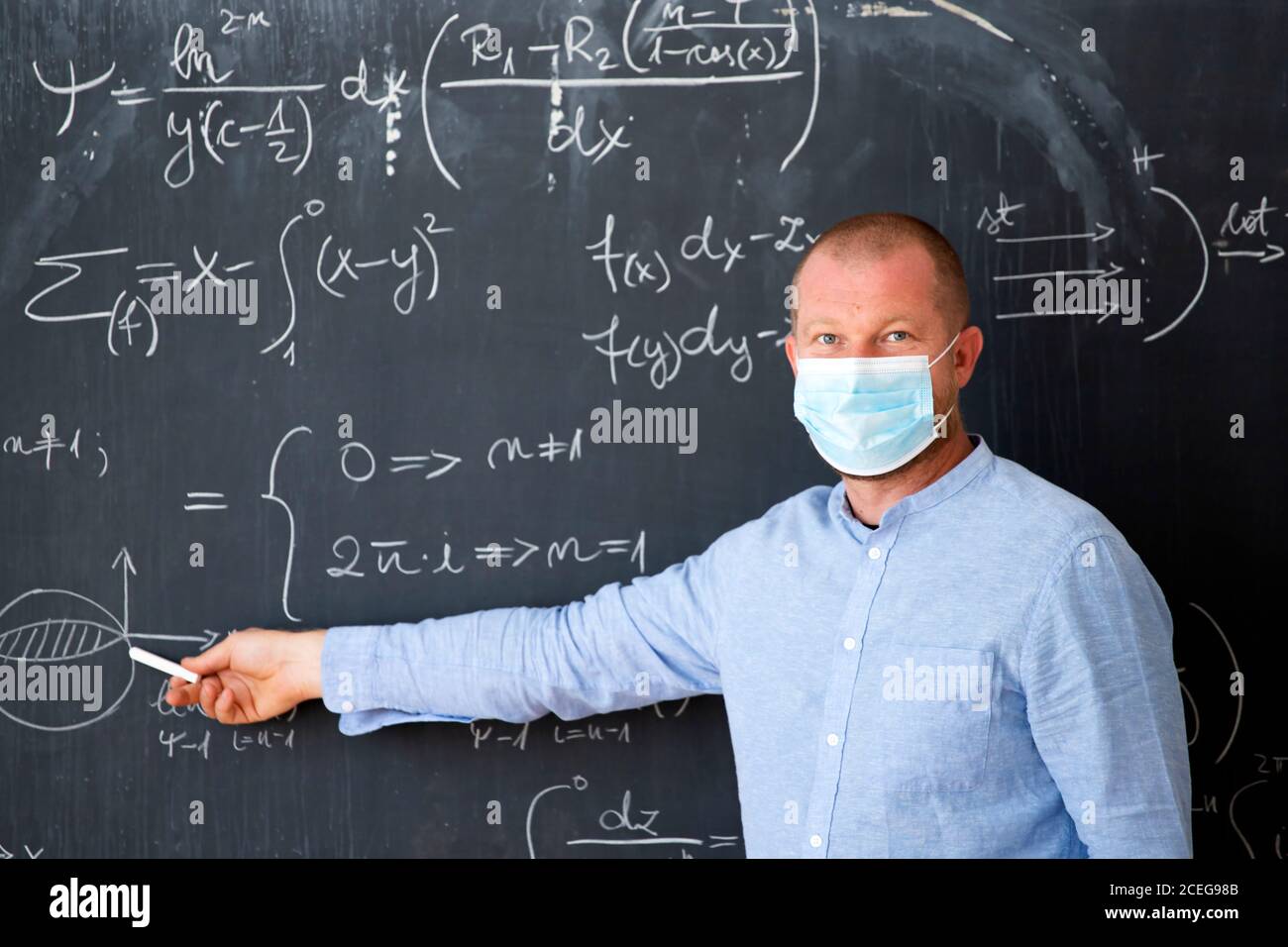 Male teacher with mask teaching math lesson at school. Social ...