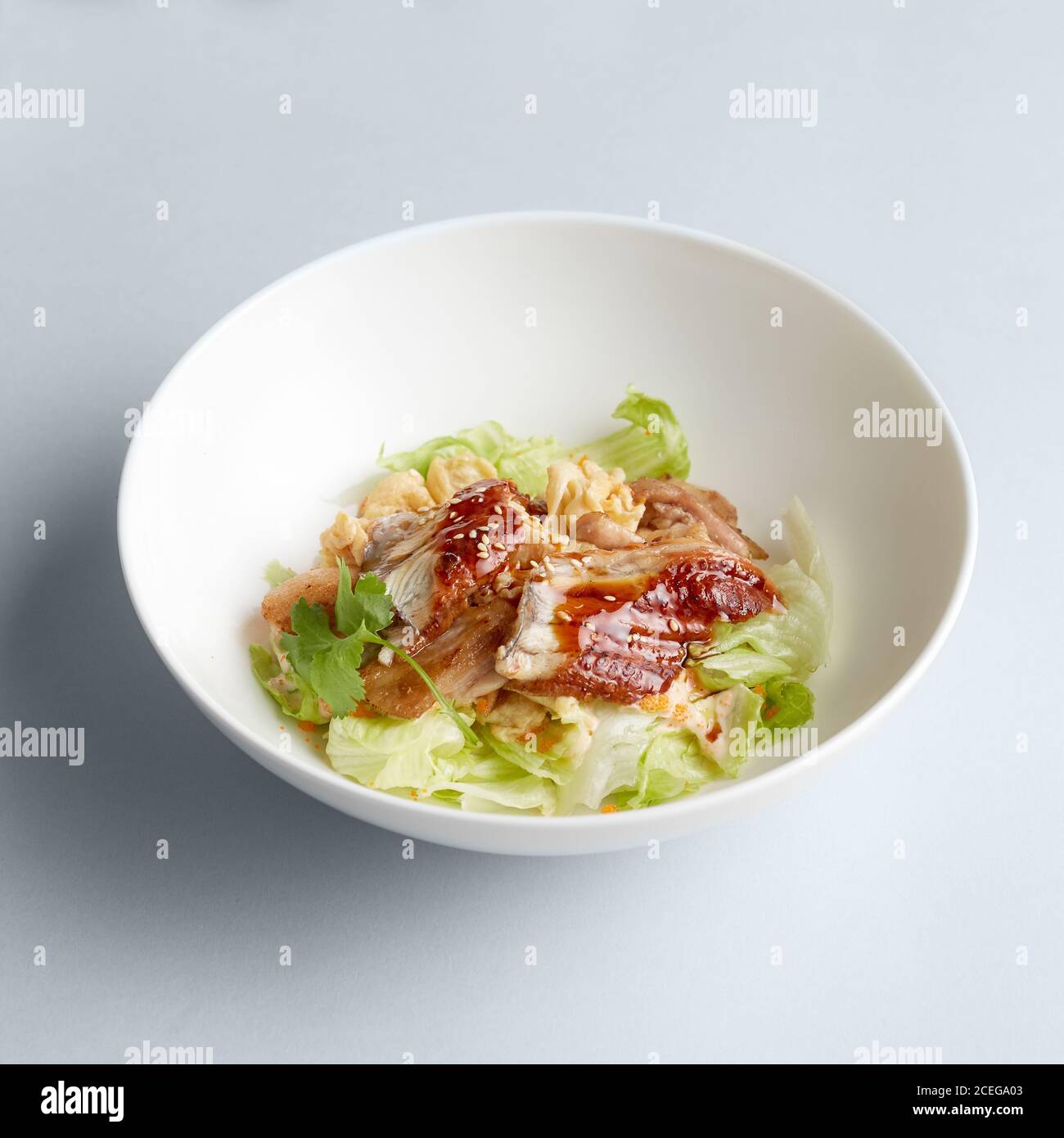 Beautiful chopped cucumbers, tomatoes and potherbs mixed in large ceramic white bowl on white background Stock Photo